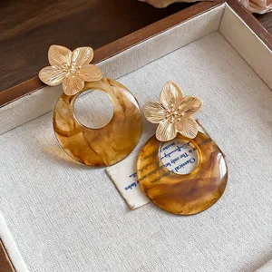 Detail of French vintage earrings featuring gold metal flowers and marbled amber resin hoops