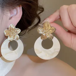 Detailed macro view of vintage French style gold flower and marbled cream resin earrings