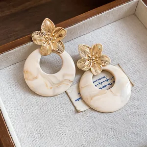 Close-up of French vintage gold flower earrings with elegant marble resin hoops