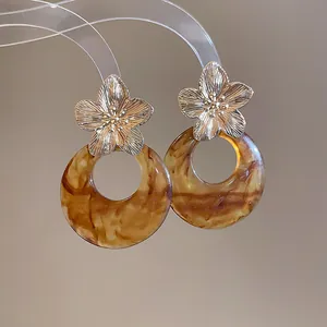 Close-up of French vintage earrings with metallic flower studs and marbled resin hoops.