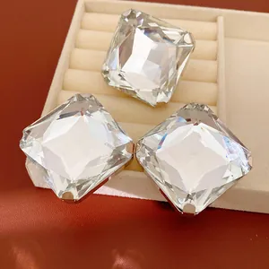 Gros plan montrant les facettes brillantes de trois grandes boucles d'oreilles en cristal.
