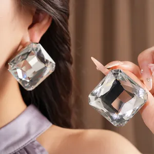 Gros plan détaillé de boucles d'oreilles carrées en cristal portées par un mannequin.