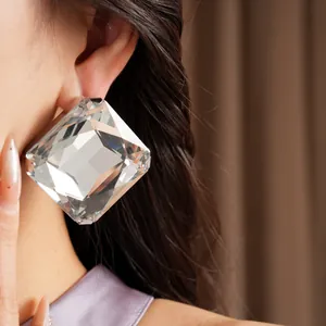 Gros plan détaillé montrant une grande boucle d'oreille carrée en cristal sur un modèle