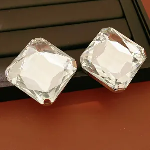 Gros plan de boucles d'oreilles carrées en cristal avec tiges en argent sur un plateau