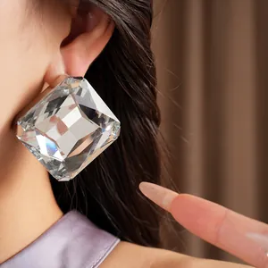 Gros plan détaillé d'une grande boucle d'oreille carrée en cristal sur l'oreille