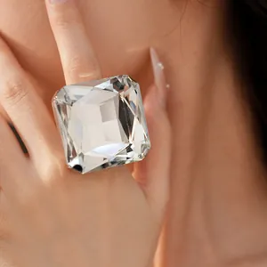 Détail d'une grande bague en cristal clair à facettes carrées portée par un mannequin.