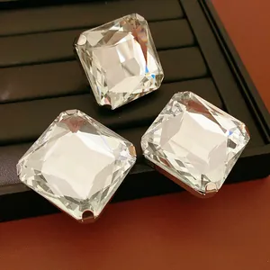 Gros plan de trois grandes boucles d'oreilles carrées en cristal avec griffes d'argent.