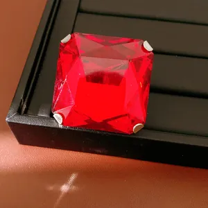 Macro detail of square red gemstone stud earring on a black display tray
