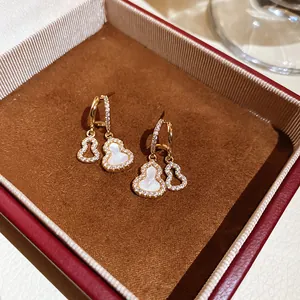 Detailed close-up of 18k gold plated gourd earrings with sparkling zircon and shell inlay