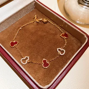 Detailed macro shot of a gold-plated Wulu bracelet featuring red enamel and zircon charms.