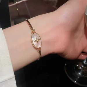 Close-up of elegant 18k gold plated bangle with mother of pearl and star motif on wrist