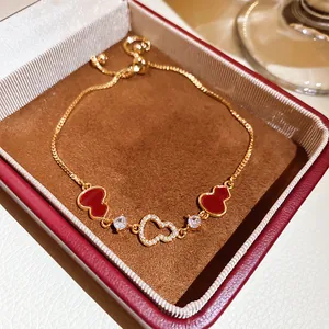Close-up of gold plated wulu and heart charm bracelet presented in a luxury jewelry gift box