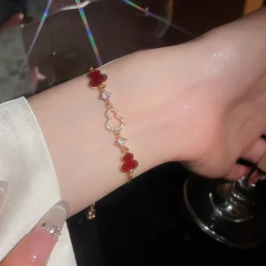 Close-up of an 18K gold plated zircon hulu charm bracelet on a delicate female wrist