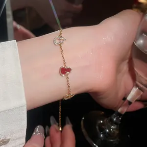 Close-up of elegant gold plated zircon bracelet with red heart and gourd charms on wrist