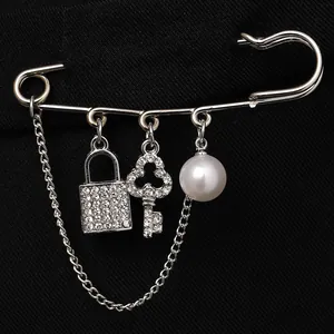 Silver safety pin brooch with crystal lock, key pendants and a white pearl charm