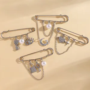 Detailed view of silver safety pin brooches with crystal moon, star, and pearl charms
