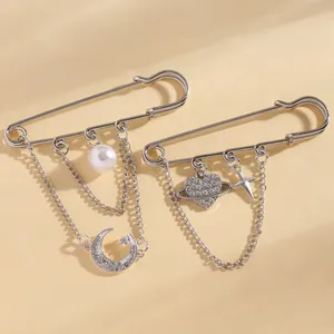 Detail shot of silver safety pin brooches with heart planet, star and moon charms