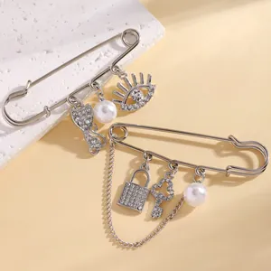 Close-up detail of silver safety pin brooches with eye, cat, and pearl charms.