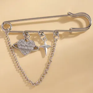 Close-up detail of silver safety pin brooch with rhinestone heart and star charms.