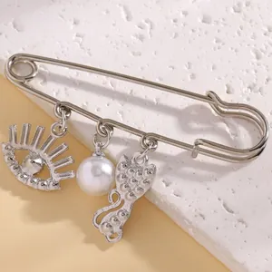 Macro shot of a silver safety pin brooch featuring unique eye pearl and cat charms