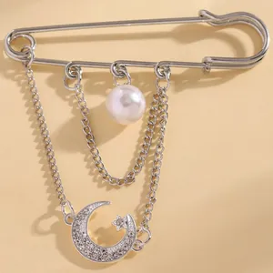 Detailed close-up of a silver safety pin brooch with pearl and moon star charms