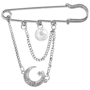 Macro view of silver safety pin brooch with moon, star charms and white pearl detail