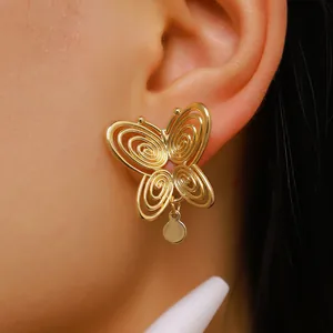 Close-up detail of hollow spiral butterfly stud earrings with gold finish on ear.