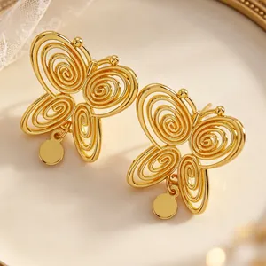 Macro detail of gold hollow spiral butterfly earrings with vintage luxury design