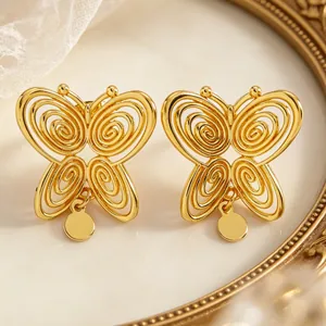 Detailed macro shot showing gold butterfly stud earrings with hollow spiral textures