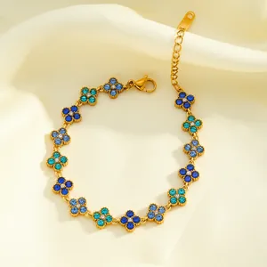 Detailed macro shot of a gold stainless steel bracelet featuring blue rhinestone flowers