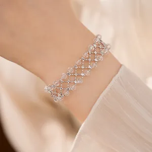 Dettaglio ravvicinato del bracciale a maglia con perline di vetro rotonde sul polso di una modella