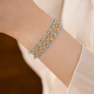 Primo piano di un bracciale a maglia con perle di vetro azzurre e dettagli dorati