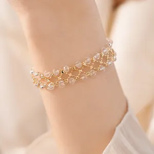 Vista dettagliata di un bracciale traforato dorato con perline di vetro al polso.
