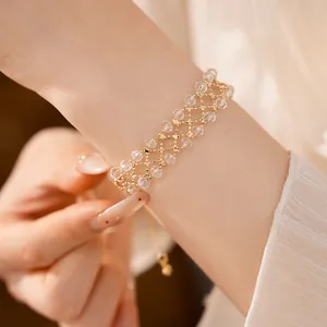 Primo piano di un elegante bracciale traforato dorato con perle di vetro trasparenti