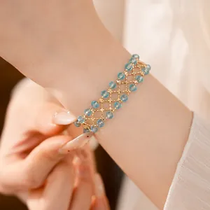 Dettaglio ravvicinato di un bracciale a griglia dorato con perline di vetro blu sfaccettate