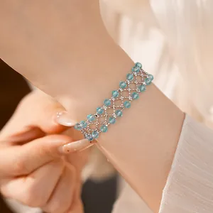 Dettaglio di un elegante bracciale in perle di vetro blu con design a rete argento.