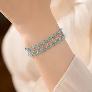 Delicato bracciale traforato con perline di vetro azzurro mostrato sul polso