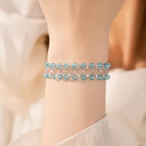 Dettaglio ravvicinato di un elegante bracciale in maglia traforata con perline blu sul polso