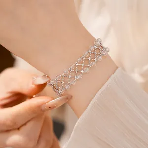 Dettaglio di un bracciale a griglia traforato con perle di vetro circolari sul polso