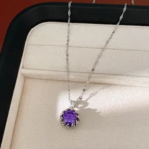 Elegante collar de plata con un colgante redondo de circonita púrpura en un joyero