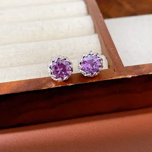 Primer plano de elegantes pendientes de botón con circonitas púrpuras en plata