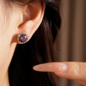 Elegante primer plano de un pendiente de circonita púrpura en la oreja de una modelo