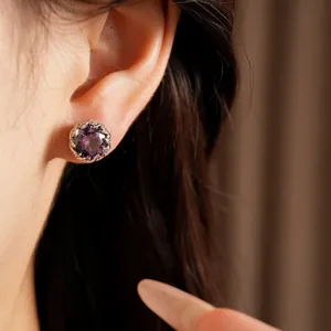 Primer plano de elegantes pendientes de circonita púrpura con borde plateado trenzado