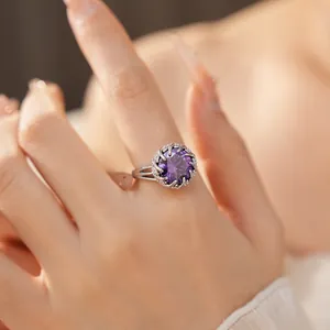 Vista detallada de un elegante anillo de plata con un gran circón púrpura y un halo.
