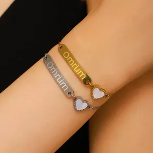 Gros plan de bracelets en acier doré et argenté avec breloques cœur portés au poignet