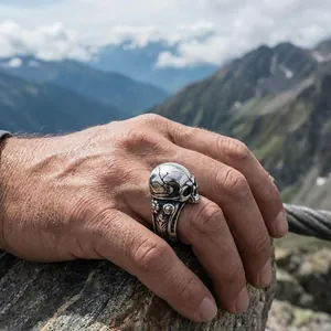 Detailed view of a vintage gothic skull ring for men in a rugged outdoor mountain setting