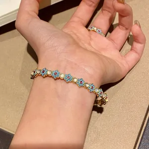 Detail shot showing floral bracelet with turquoise enamel and cat's eye stone on wrist