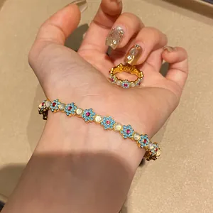 Detailed view of floral enamel bracelet and ring set with sparkling cat's eye stones