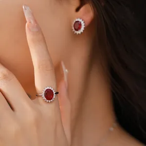 Gros plan d'une bague et de boucles d'oreilles élégantes avec pierres rouges ovales sur modèle
