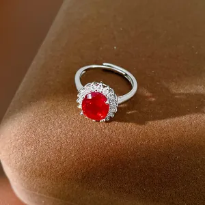 Gros plan d'une bague en argent ornée d'une pierre rouge entourée de zircons clairs.